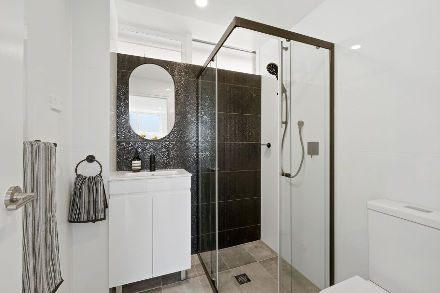 Bathroom with black shower and white vanity