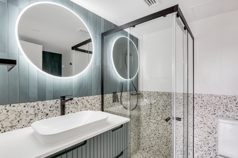 Stylish bathroom with illuminated round mirror