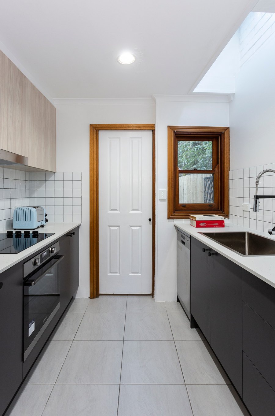 Narrow kitchen with white tiled walls